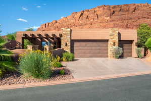 Desert contemporary architecture featuring a stucco exterior with stone accents, a multi-car garage, and xeriscaped landscaping