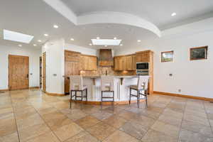 Spacious kitchen featuring warm wood cabinetry, built-in stainless steel appliances, a curved breakfast bar with paneled detailing, and an integrated microwave