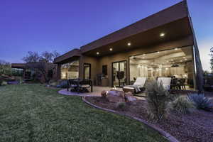 Back of property at dusk with stucco siding, a patio, a yard, and outdoor dining space