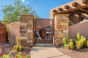 Wrought iron gate with decorative metalwork, flanked by stone pillars and desert landscaping