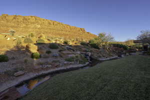 View of grassy yard with a mountain view and a garden pond
