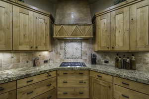Kitchen with stainless steel gas stovetop, light wood finish cabinets, and tasteful backsplash