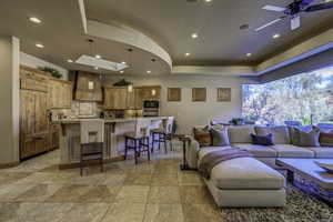 Living room with a skylight, ceiling fan, light stone finish flooring, and recessed lighting