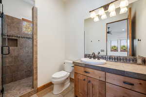 Bathroom featuring a tiled shower with a built-in niche and a window, a single vanity with a vessel sink, dark bronze fixtures, a tile countertop, and a mirrored backsplash