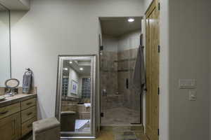 Full bath featuring vanity, a shower stall, and stone tile flooring