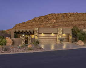 View of front of property with an attached garage, concrete driveway, stone siding, and a mountain view