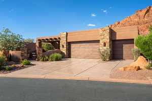 Southwestern-style stucco exterior with stone accents, featuring two distinct garage doors and a multi-car driveway