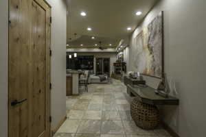 Hall featuring recessed lighting, a tray ceiling, and light stone finish flooring