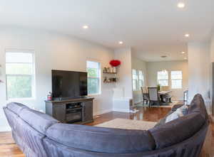 Living area with light wood-type flooring and recessed lighting