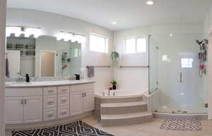 Full bath featuring double vanity, a shower stall, healthy amount of natural light, a garden tub, and recessed lighting
