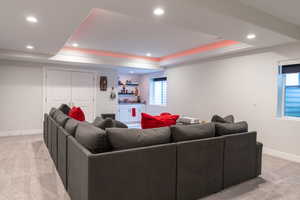 Carpeted living room with recessed lighting, a raised ceiling, and bar area