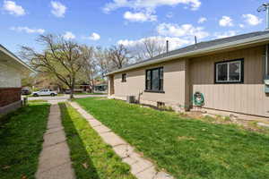 View of home's exterior with a lawn, brick siding, and roof with shingles