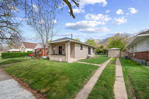 View of front of property featuring brick siding, covered porch, a mountain view, and an outbuilding