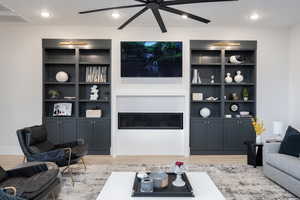 Living area with light wood-type flooring, built in shelves, recessed lighting, and ceiling fan