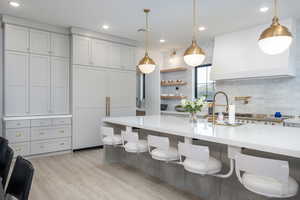 Kitchen featuring backsplash, light stone countertops, light wood-style flooring, and a breakfast bar
