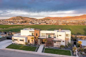 View of front of house featuring a front lawn, stucco siding, a mountain view, and a view of countryside