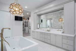 Bathroom with double vanity, a freestanding tub, and recessed lighting
