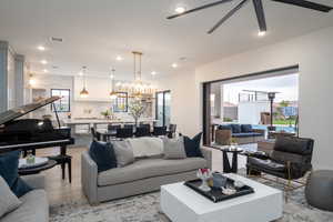 Living room with wood finished floors, hanging lights, and a ceiling fan