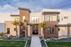 View of front of home with a front lawn, stucco siding, and covered porch