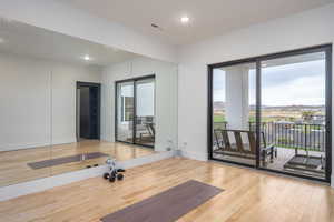 Workout area with light wood-style flooring and recessed lighting
