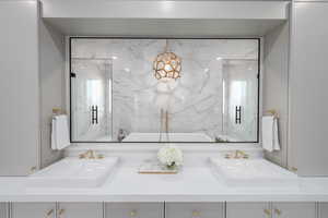 Full bath featuring double vanity and a marble finish shower