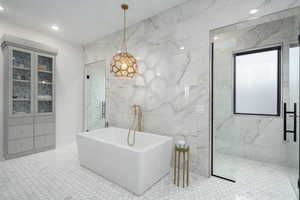 Bathroom featuring tile walls, a marble finish shower, a freestanding bath, and recessed lighting