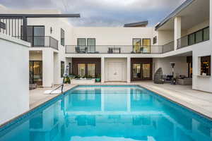 Rear view of house featuring stucco siding, outdoor lounge area, an outdoor pool, a patio, and a balcony