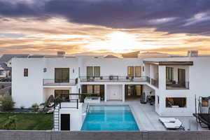 Rear view of house featuring an outdoor pool, stucco siding, a balcony, and a patio