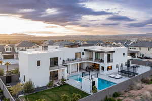 Back of property featuring a balcony, a fenced backyard, stucco siding, a residential view, and a patio area