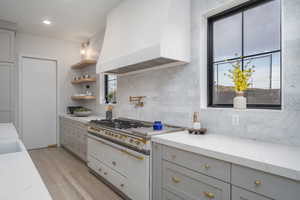 Kitchen featuring gray cabinets, range with two ovens, healthy amount of natural light, and light stone countertops