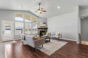 Living area featuring dark wood finished floors, a ceiling fan, a fireplace, a high ceiling, and recessed lighting