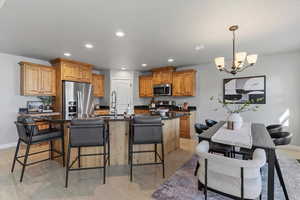 Kitchen with a kitchen island with sink, hanging lights, a breakfast bar, stainless steel appliances, and dark stone counters