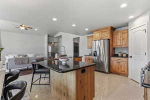 Kitchen with stainless steel appliances, a center island with sink, open floor plan, a breakfast bar area, and recessed lighting
