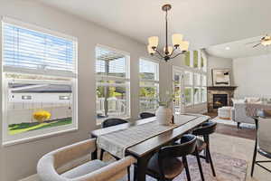Dining room with a stone fireplace, a ceiling fan, suspended lighting, and light wood finished floors