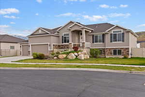 View of front facade with stone siding, stucco siding, an attached garage, and driveway