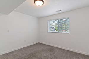 Empty room featuring baseboards and dark carpet