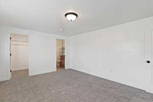 Unfurnished bedroom featuring a spacious closet, carpet floors, and ensuite bathroom