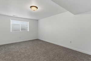 Spare room with baseboards and dark colored carpet