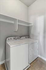 Laundry area with independent washer and dryer and light tile patterned flooring
