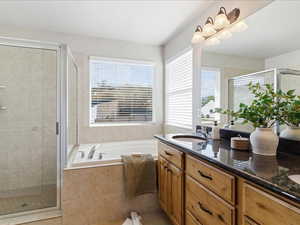 Full bathroom featuring double vanity, a garden tub, and a stall shower