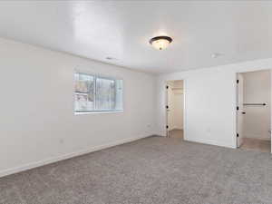 Unfurnished bedroom with a walk in closet and carpet