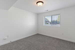Unfurnished room with baseboards and dark carpet
