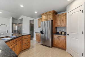 Kitchen with stainless steel refrigerator with ice dispenser, dark stone countertops, and recessed lighting