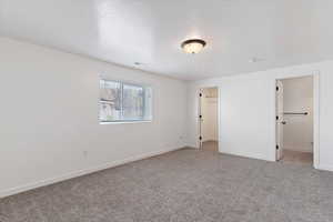 Unfurnished bedroom with a spacious closet, ensuite bathroom, and carpet floors