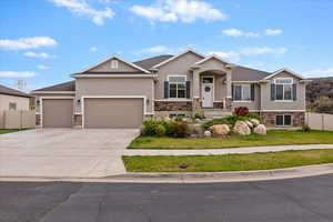 View of front of home with stone siding, stucco siding, a garage, and driveway