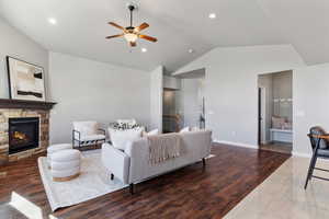 Living area featuring wood finished floors, a ceiling fan, vaulted ceiling, a fireplace, and recessed lighting