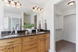 Full bathroom with a spacious closet, double vanity, light carpet, and connected bathroom