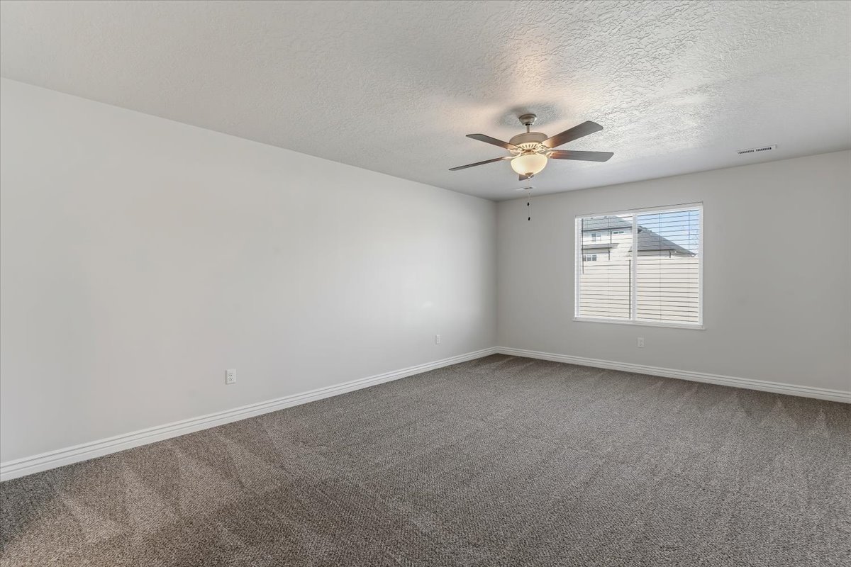 Unfurnished room featuring dark carpet, a ceiling fan, and a textured ceiling