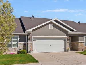 Ranch-style home with stone siding, driveway, a garage, and a front lawn
