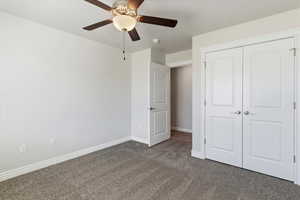 Unfurnished bedroom with dark colored carpet, a closet, a ceiling fan, and a textured ceiling